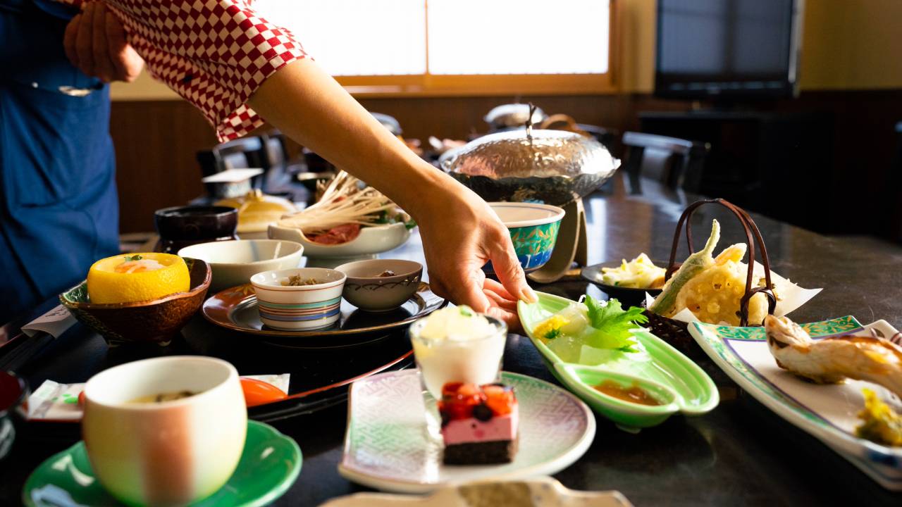 秩父の須崎旅館の女将が、部屋食のお客様用に料理をテーブルに並べている